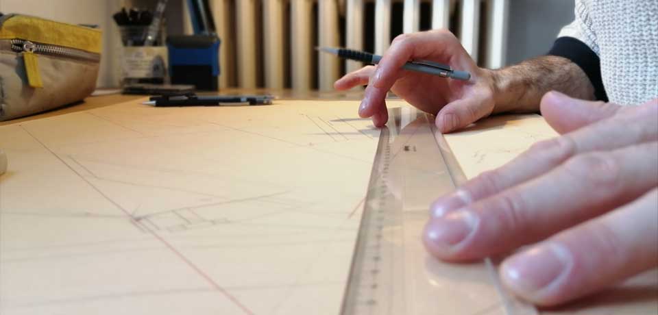 Tracé au crayon et règle tenue par deux mains
